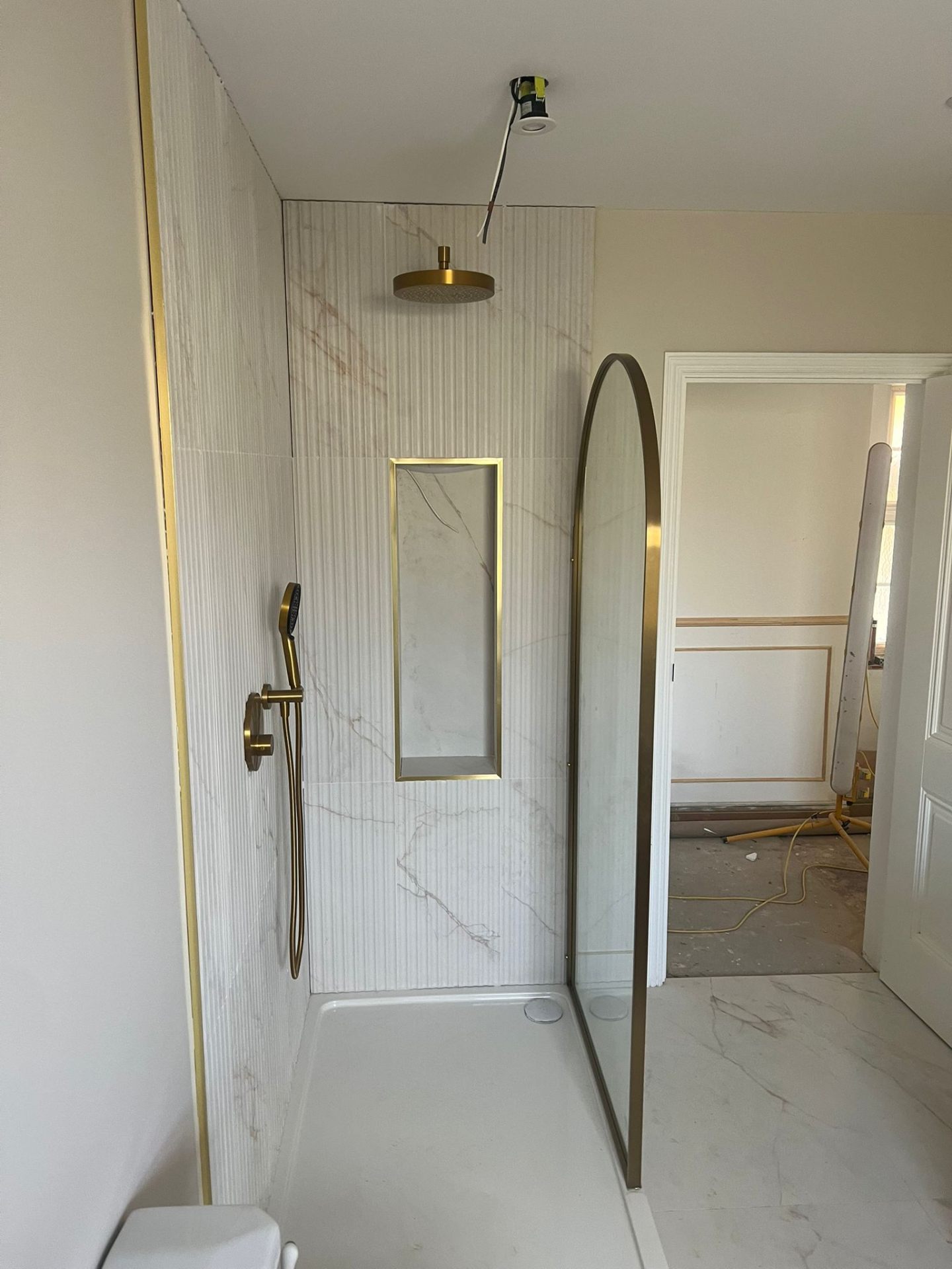 Luxury walk-in shower enclosure with brass fittings and marble tiles, Essex