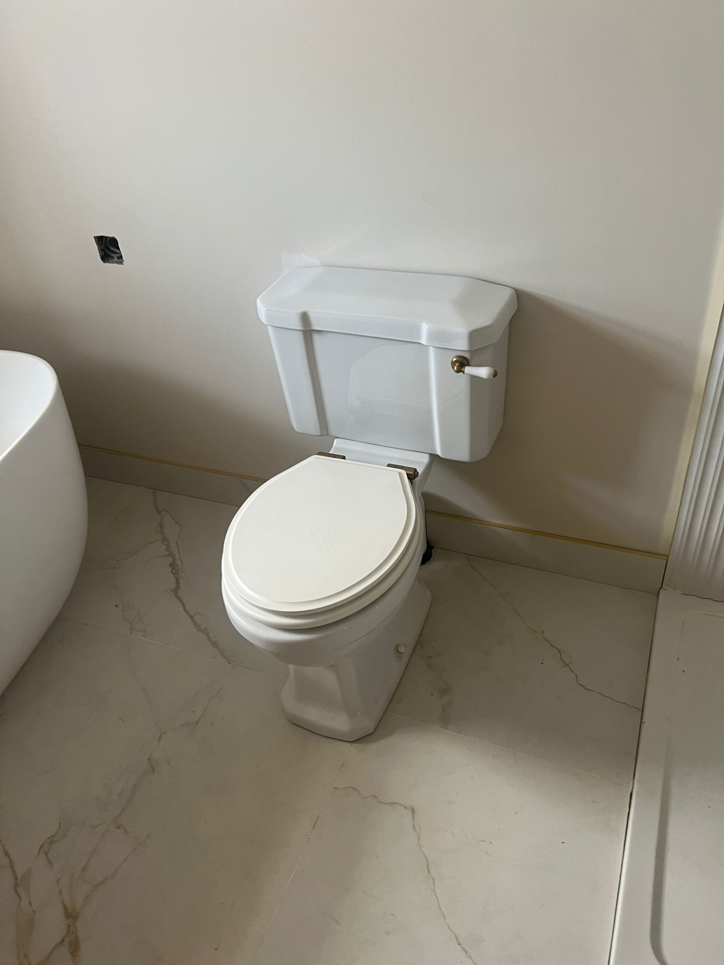 Traditional close-coupled WC with brass lever and marble floor tiles — Avanza bathroom, Essex