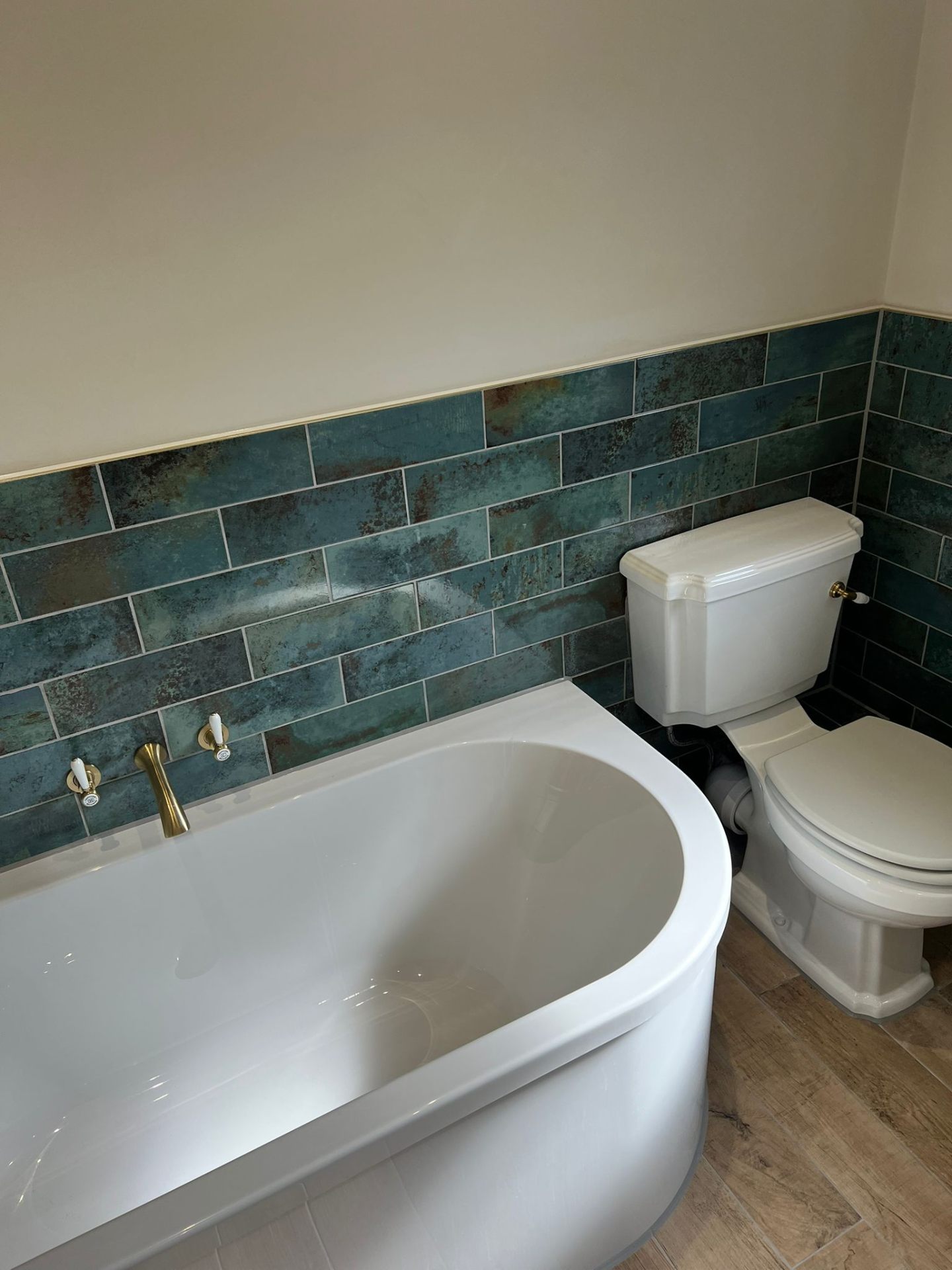 Luxury bathroom with freestanding bath, brass taps and teal tiles, Essex