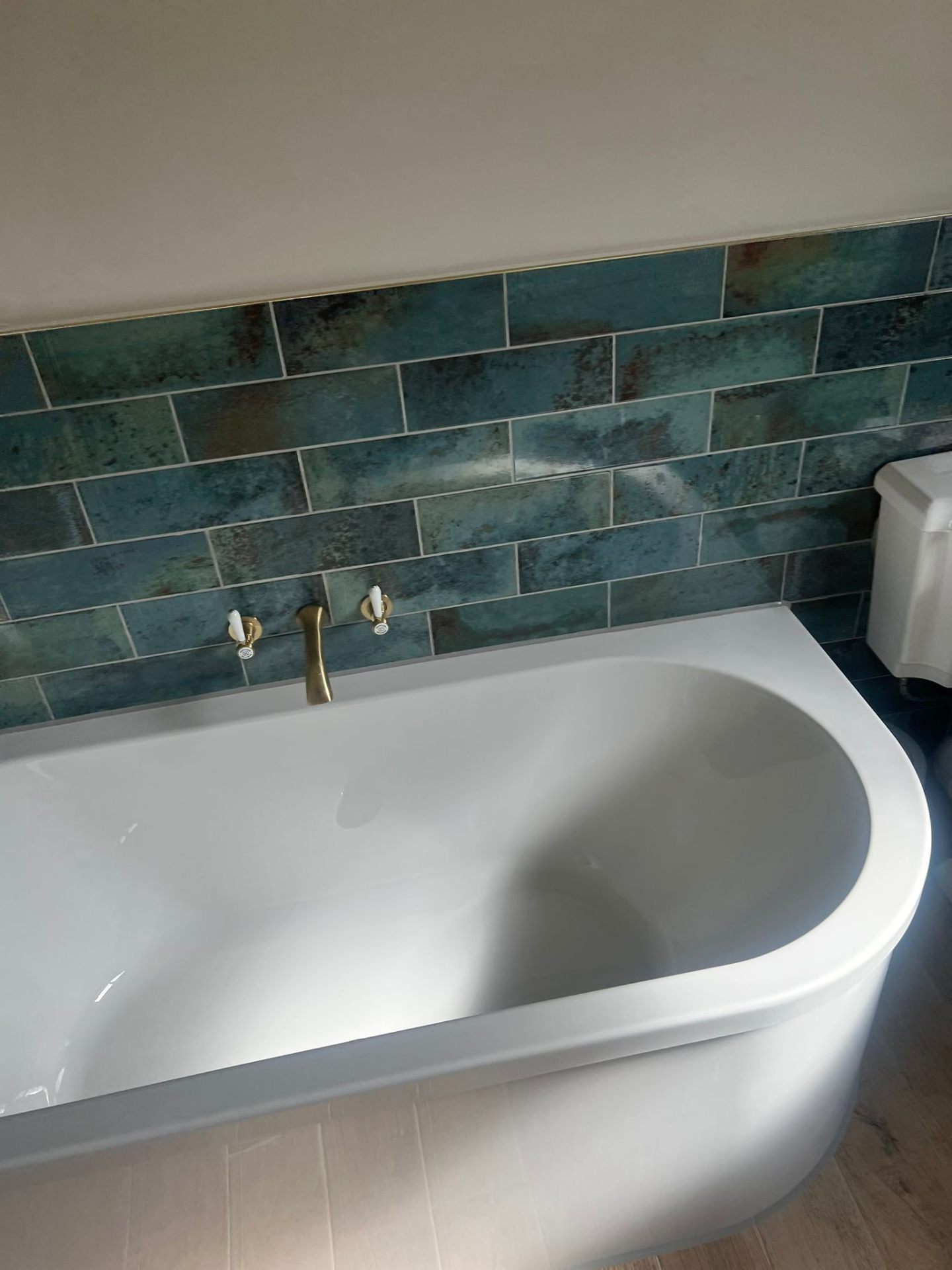 Freestanding bath with brass wall taps and teal tiles, Essex