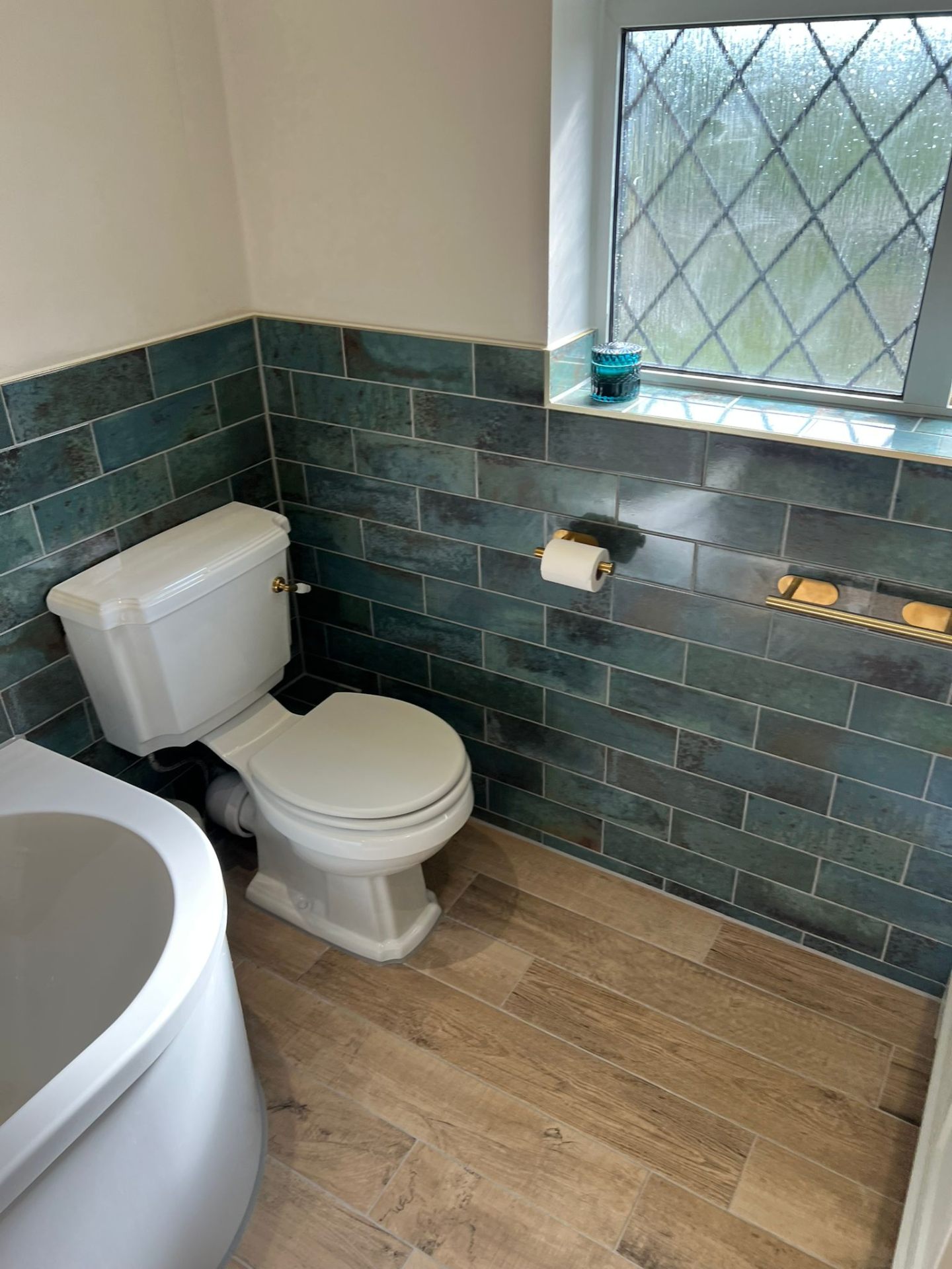 Bathroom installation with toilet, freestanding bath and teal tiles, Essex